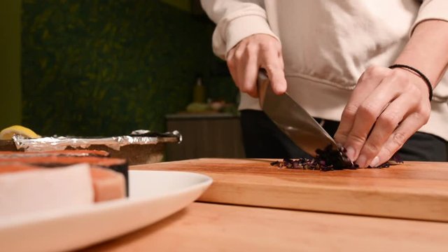 Closeup of the hands of a girl at the home kitchen on a wooden cutting board small cherry tomatoes. Home cooking