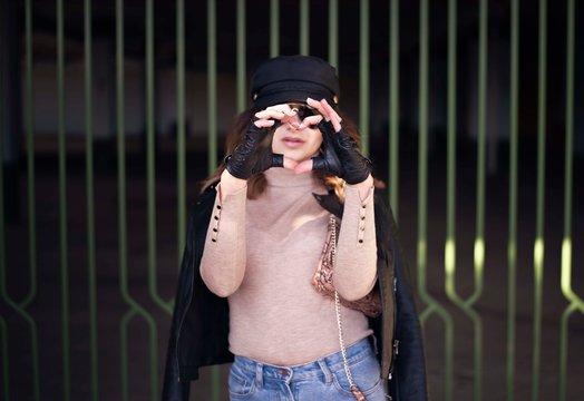 Street fashion outdoor photo of woman with dark hair in black leather jacket and sunglasses in defocus. Woman gesturing HEART with her hands - LOVE image