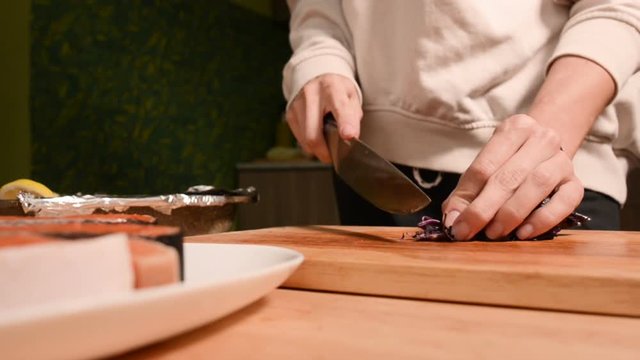 Closeup of the hands of a girl at the home kitchen on a wooden cutting board small cherry tomatoes. Home cooking