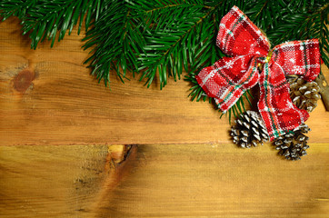 Red bow with fir tree branch and snowy pine cones on wooden background. Christmas background. Xmas time