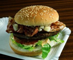 Bocadillo con un Panecillo de semillas, una hamburguesa, lechuga, tomate, beicon y cebolla.