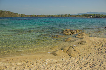 Caribbean sea rocky stone and sand shoreline south summer scenery landscape with vivid blue color tropic water surface and clear weather time