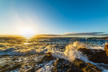 Waves crashing against the rocky shore at sunset