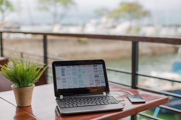 Laptop on wooden table at the yacht club cafe with online business via WiFi Hotspot tethering 