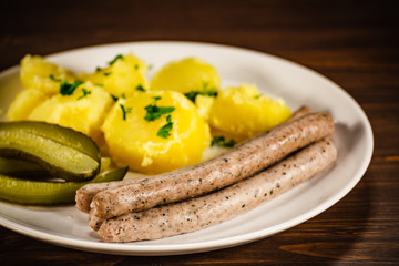 Boiled white sausages and vegetables on wooden table