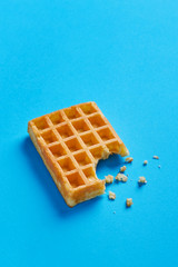Single fresh waffle isolated on a blue background viewed from above. Copy space
