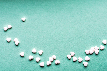 Fototapeta na wymiar Small white hearts on a green background. Greeting card for Valentine's Day. Free space