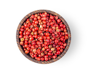 pink peppercorn in wood bowl isolated on white background. top view