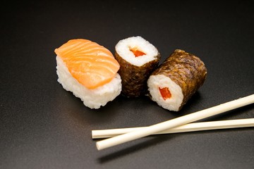 sushi with chopsticks on black background