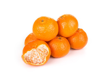 Stack of tangerine with  the one partially peeled.