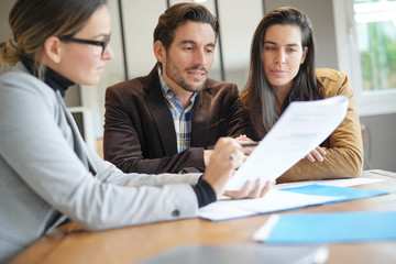 Attractive couple signing sales agreement with real estate agent