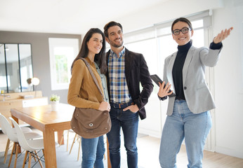 Real estate agent showing modern house to attractive couple - obrazy, fototapety, plakaty