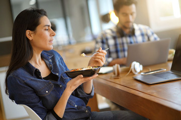 Beautiful woman eating lunch whilst working in co working space