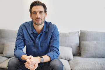 Isolated handsome man in denim on comfortable couch