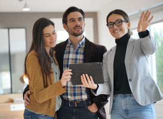 Real estate agent showing modern house to attractive couple