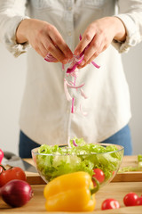 The girl prepares a salad of fresh vegetables. Vertical photo.