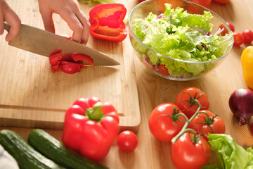Girl cuts sweet pepper in vegetable salad. Cooking salad.
