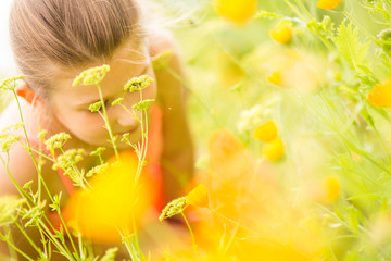 Young girl smelling flowers on the meadow