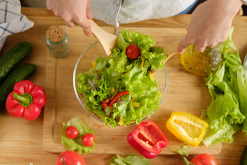 Girl interferes with vegetable salad. Cooking salad