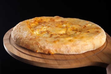 Georgian traditional food khachapuri on the wooden dish on black background