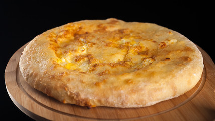 Georgian traditional food khachapuri on the wooden dish on black background