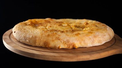 Georgian traditional food khachapuri on the wooden dish on black background