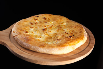 Georgian traditional food khachapuri on the wooden dish on black background