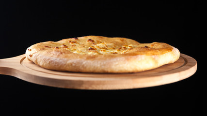 Georgian traditional food khachapuri on the wooden dish on black background