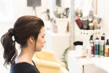 Brunette with wavy ponytail at hair salon - obrazy, fototapety, plakaty