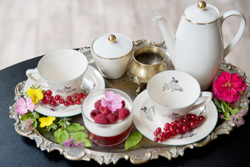 Magnificent fresh hot tea in ancient cups on a silver vintage tray and a raspberries dessert, an antique teapot