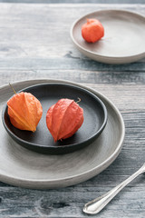 Two physalis on a rustic background, old-fashioned fork