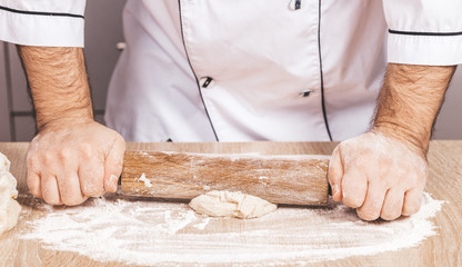 male cook kneads dough on the table