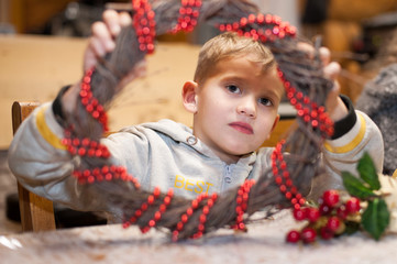 Portrait of a boy with a Christmas wreath decorated with red beads