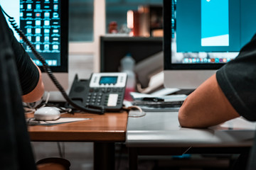 End of the year, last days in office for graphic designers in printing facility, details of telephones, computer screens and desks. Simmetric shot, artificial lighting, no faces.