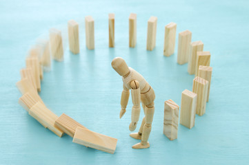 Thoughtful confused wooden dummy building circle domino puzzle and making mistake