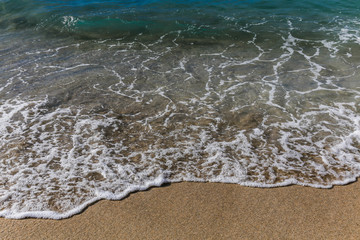 frothy bubbles in the ocean as little waves come onto beach