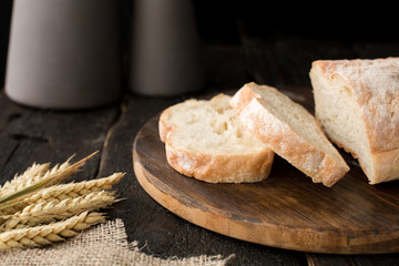 Fresh bread on a board with wheat on a wooden background