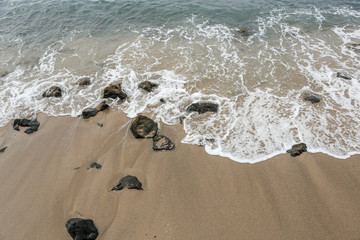 small wave on the beach with scattered rocks
