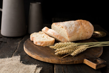 Fresh bread on a board with wheat on a wooden background