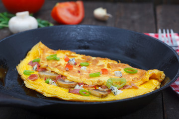 Cooking egg omlette with ham, mushrooms and pepper in a pan.