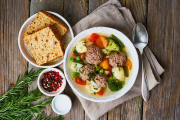 meatballs soup in white plate on old wooden rustic grey table, top view