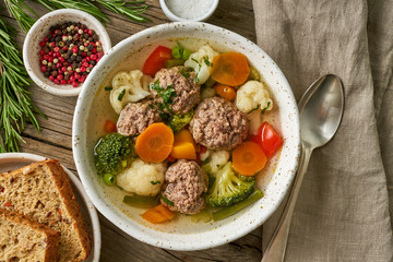 meatballs soup in white plate on old wooden rustic grey table, top view