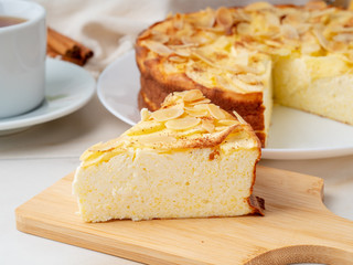 Cheesecake, apple pie, curd dessert with polenta, apples, almond flakes and cinnamon on white marble kitchen table, side view