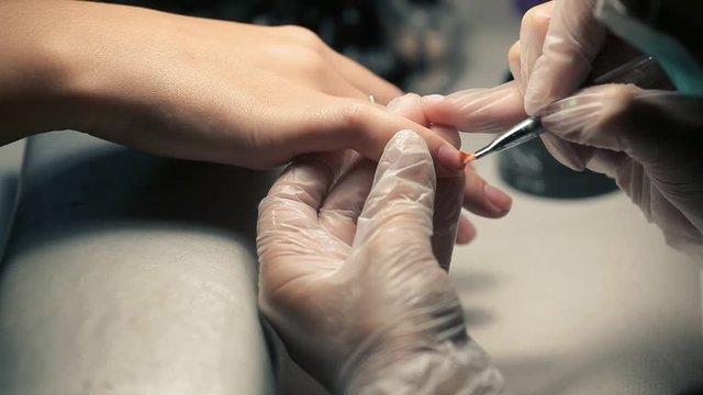 Master makes a manicure to young girl. Working with nails in a beauty salon.