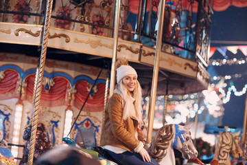 A young woman rides a merry-go-round with horses at the New Year Fair attraction horse