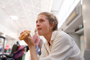 Young woman, authentic, natural, unplugged, waiting for her flight at the airport of Tenerife while eating a bun.