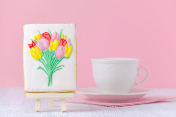 gingerbread with flowers on the painting easel with coffe cup on pink background