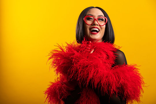 Pretty Asian woman wearing vibrant red feather boa and heart shaped glasses