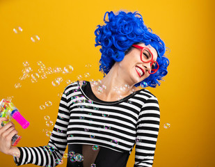 Cute girl wearing vibrant blue wig playing and blowing bubbles