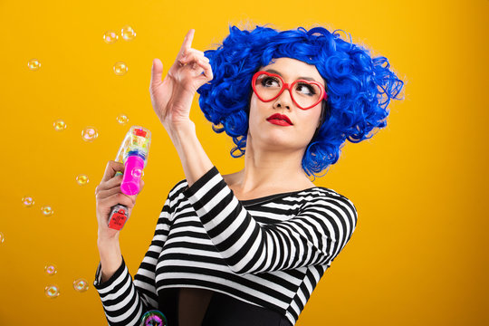 Cute girl wearing vibrant blue wig playing and blowing bubbles